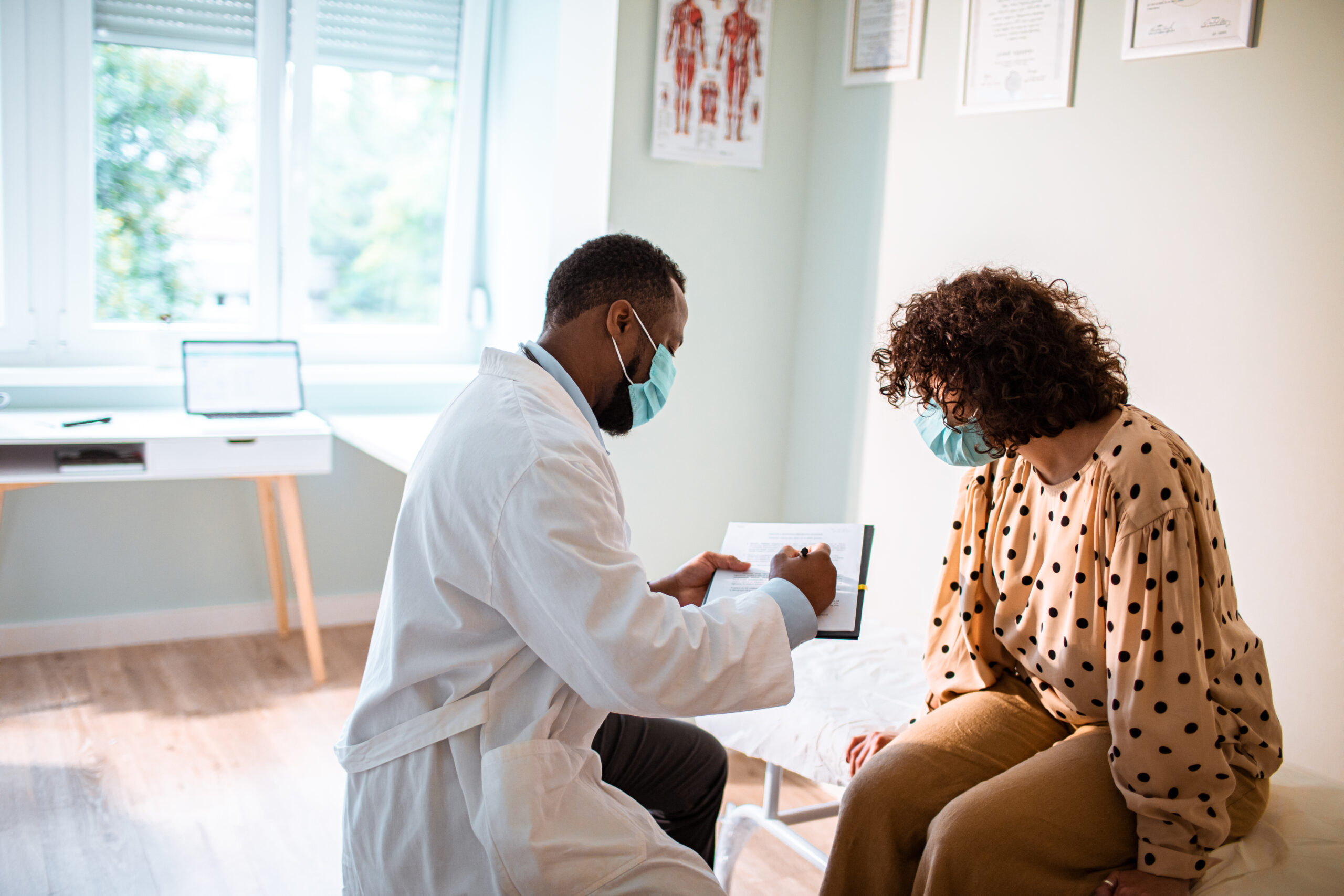 Close up of a doctor doing a medical exam while both him and the patient are wearing protective masks